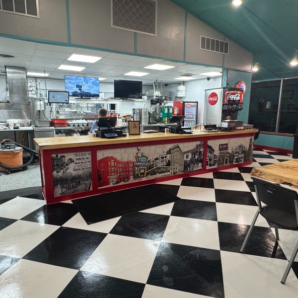 Interior of Lou Ann's Biscuits & Burgers with a counter, kitchen, and checkerboard floor.
