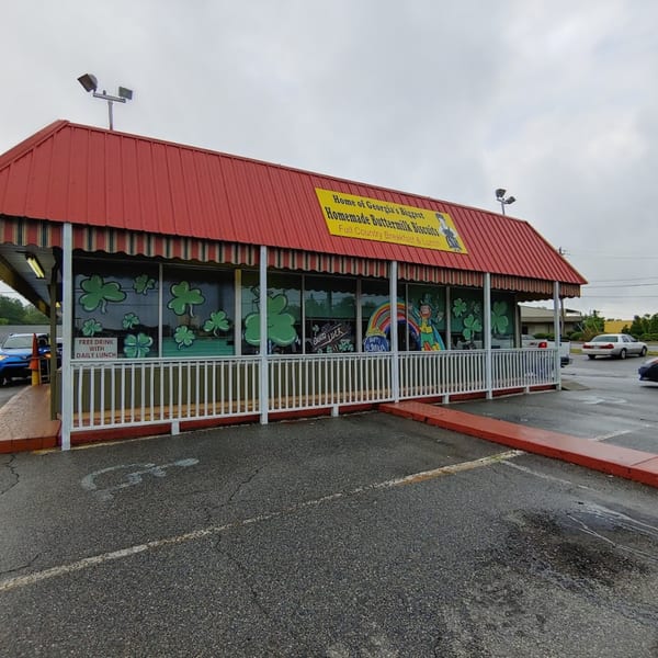 Lou Ann's Biscuits & Burgers restaurant exterior with a red roof, striped awning, and shamrock window decals.